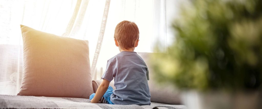 Child sits in front of window